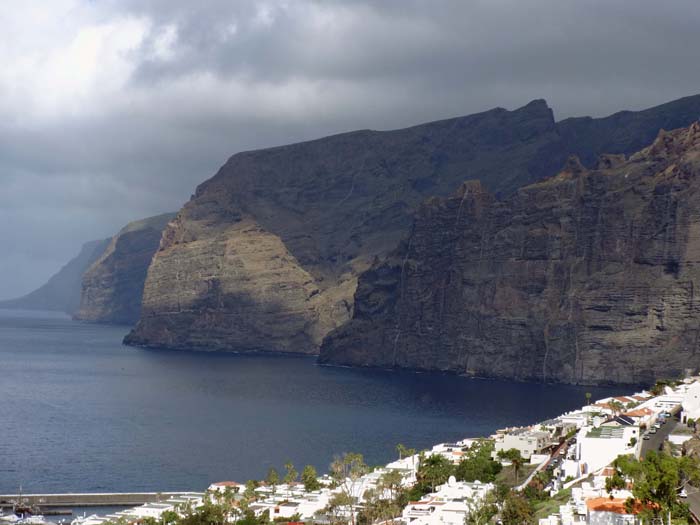 die Playa de Barranco Seco versteckt sich hinter dem dunklen Felsgrat in Bildmitte; wir durchstechen im letzten Teil der Wanderung die Wand rechts davon in einem 1000 m langen Tunnel, erreichen das Tageslicht in 200 m Höhe und queren anschließend auf von Weitem kaum sichtbaren Pfaden hoch über dem Atlantik die gesamten verbleibenden Abstürze bis zum Ferienort Los Gigantes