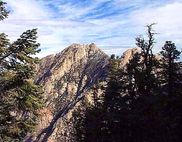 Blick vom Sattel gegen Osten. Die Teufelsschlucht mit dem Campo Noche, einem bevorzugten Biwakplatz, trennt uns von der Westflanke des Picacho del Diablo, durch welche der Normalweg führt. Die von den Bäumen rechts verdeckte Felsbastion gehört zum Pinnacle Ridge