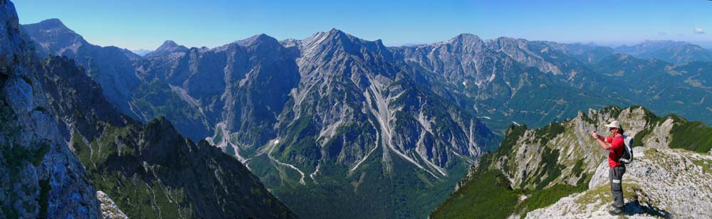 wenige Minuten später haben wir die Gipfelwand des Fäustling gequert (direkte Erkletterung ebenfalls möglich) und stehen auf der obersten Schulter des Westgrates zum Föhrengrabeneck; unter uns die Röll, darüber von links Rotgschirr, Almtaler Sonnenuhr (s. Archiv Bergsteigen), Woising und Feigentalhimmel; ganz hinten sind noch Zimnitz, Schafberg und Höllengebirge zu erkennen