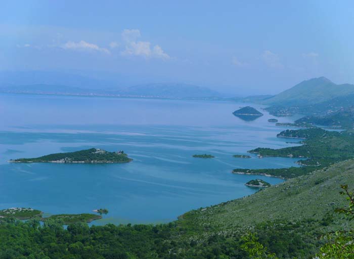 die Südecke des Skadarsees, am jenseitigen Ufer die albanische Stadt Shkodër; Albanien ist ein tolles Reiseziel voller positiver Überraschungen geworden, man sollte das Land unbedingt jetzt bereisen, bevor der zunehmende Tourismus es austauschbar macht