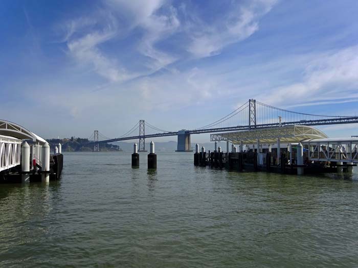 an der Ostseite des Financial District überspannt die Oakland Bay Bridge die Bucht von San Francisco, hier vom Pier 2; die Brücke mit über 8 km Länge wurde ein halbes Jahr vor der Golden Gate Bridge eröffnet, pro Tag überqueren hier über eine Viertel Million Fahrzeuge auf zwei Ebenen die Bay