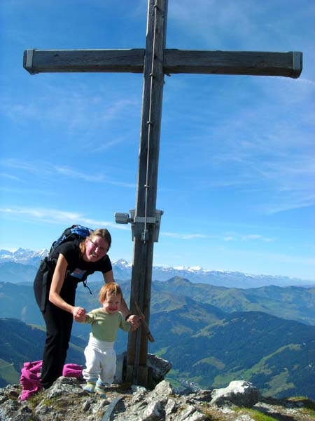 Mutter und Tochter am Gipfelkreuz, dahinter Salzburger Schieferalpen und Hohe Tauern