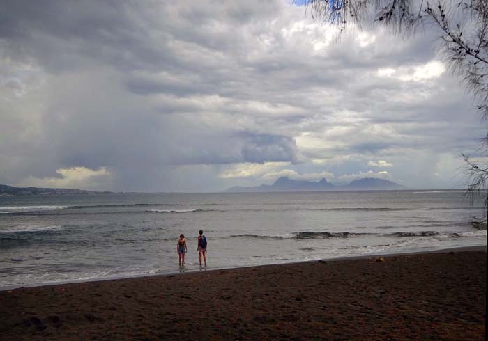 am schwarzen Sandstrand der Pointe Venus mit Blick auf die Nachbarinsel Moorea