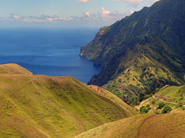 das Gelände senkt sich hin zur Jungfrauenbucht und ähnelt jetzt tatsächlich einer Almenlandschaft; ursprünglich hatte Fatu Hiva mehrere Tausend Einwohner, bis im 19. Jahrhundert Walfänger die Tuberkulose auf die Insel brachten, welche die Bevölkerung auf etwa ein Zehntel schrumpfen ließ