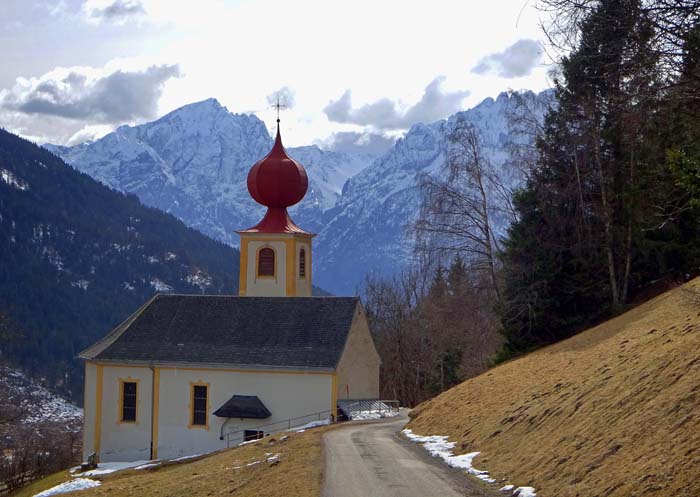 unser Aufstieg beginnt 500 m hinter der Bergkirche St. Benedikt mit Blick auf Hochstadel und Keilspitzgruppe der Lienzer Dolomiten; keine Angst: selbst wenn die Hänge hier schon aper sind, trägt heute die Forststraßentrasse noch ab dem Parkstreifen ausreichend Schnee